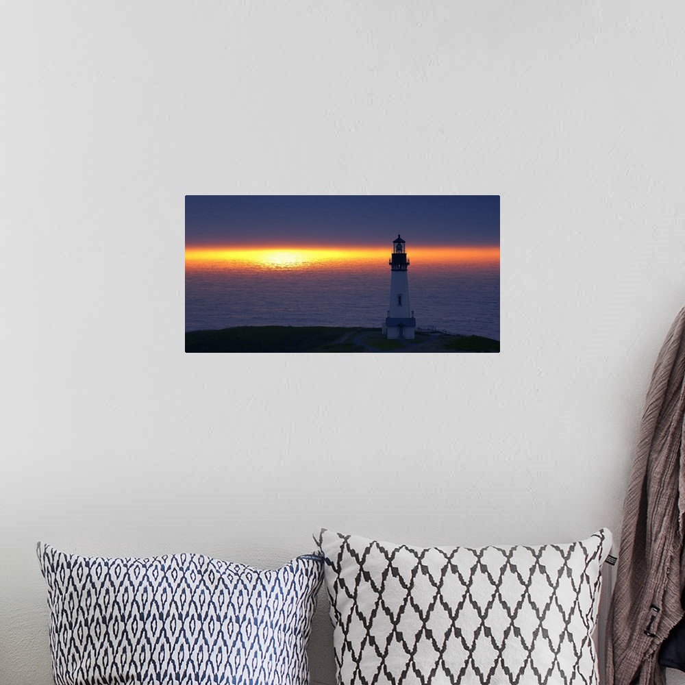 A bohemian room featuring Landscape photograph of an unlit lighthouse at sunset by the ocean.