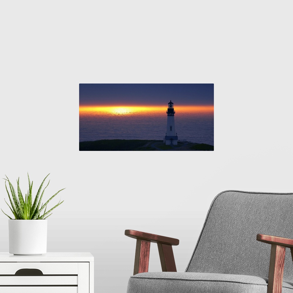 A modern room featuring Landscape photograph of an unlit lighthouse at sunset by the ocean.