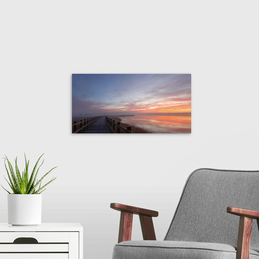 A modern room featuring Pastel sunlight on clouds at dawn over a bridge in Denmark.