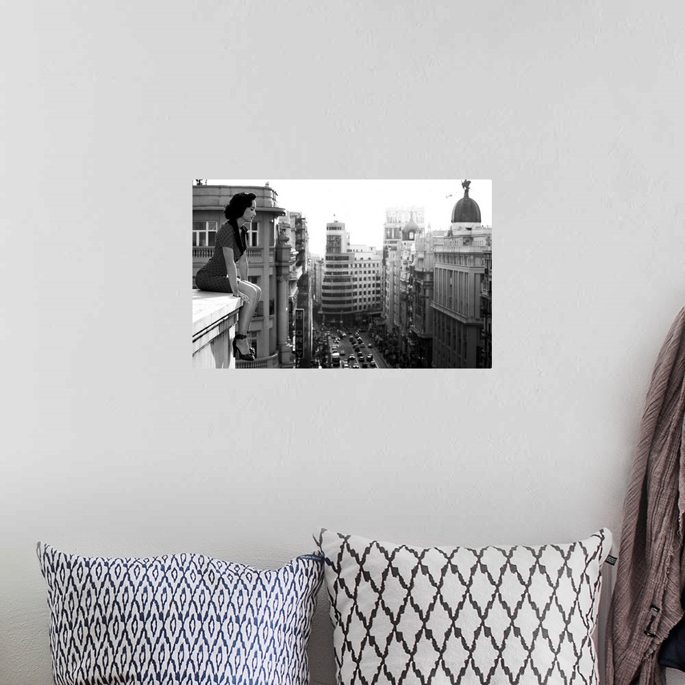 A bohemian room featuring A woman sits on a ledge overlooking  the streets of Madrid.