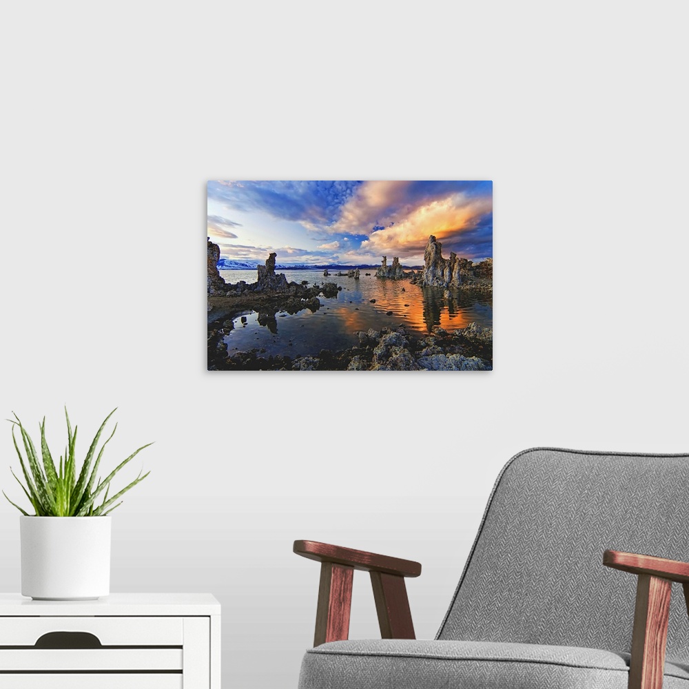 A modern room featuring A photograph of jagged rough looking rocks in a lake under dramatic clouds.