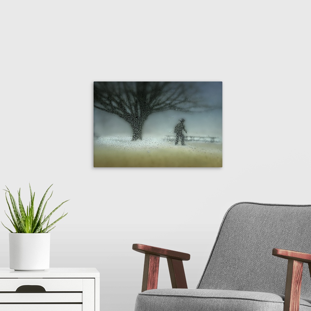 A modern room featuring Figure and bare branched tree behind frosted glass with condensation.