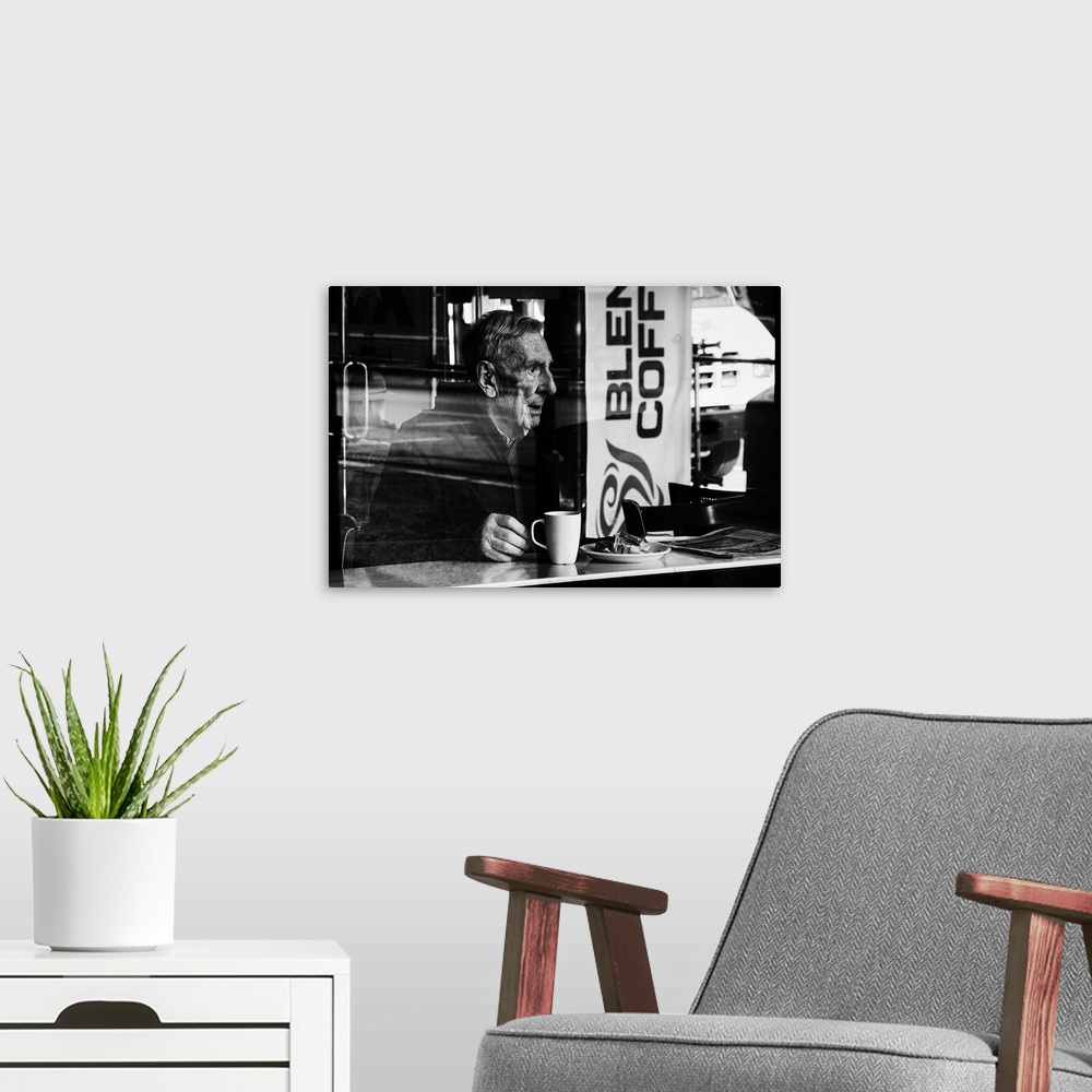 A modern room featuring A photograph of an older man sitting in a cafe drink a cup of coffee.
