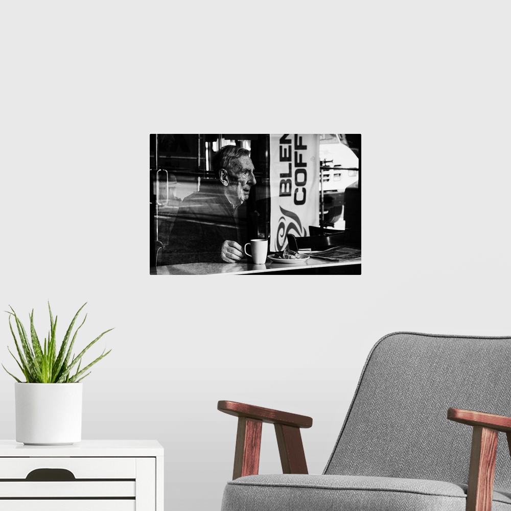 A modern room featuring A photograph of an older man sitting in a cafe drink a cup of coffee.