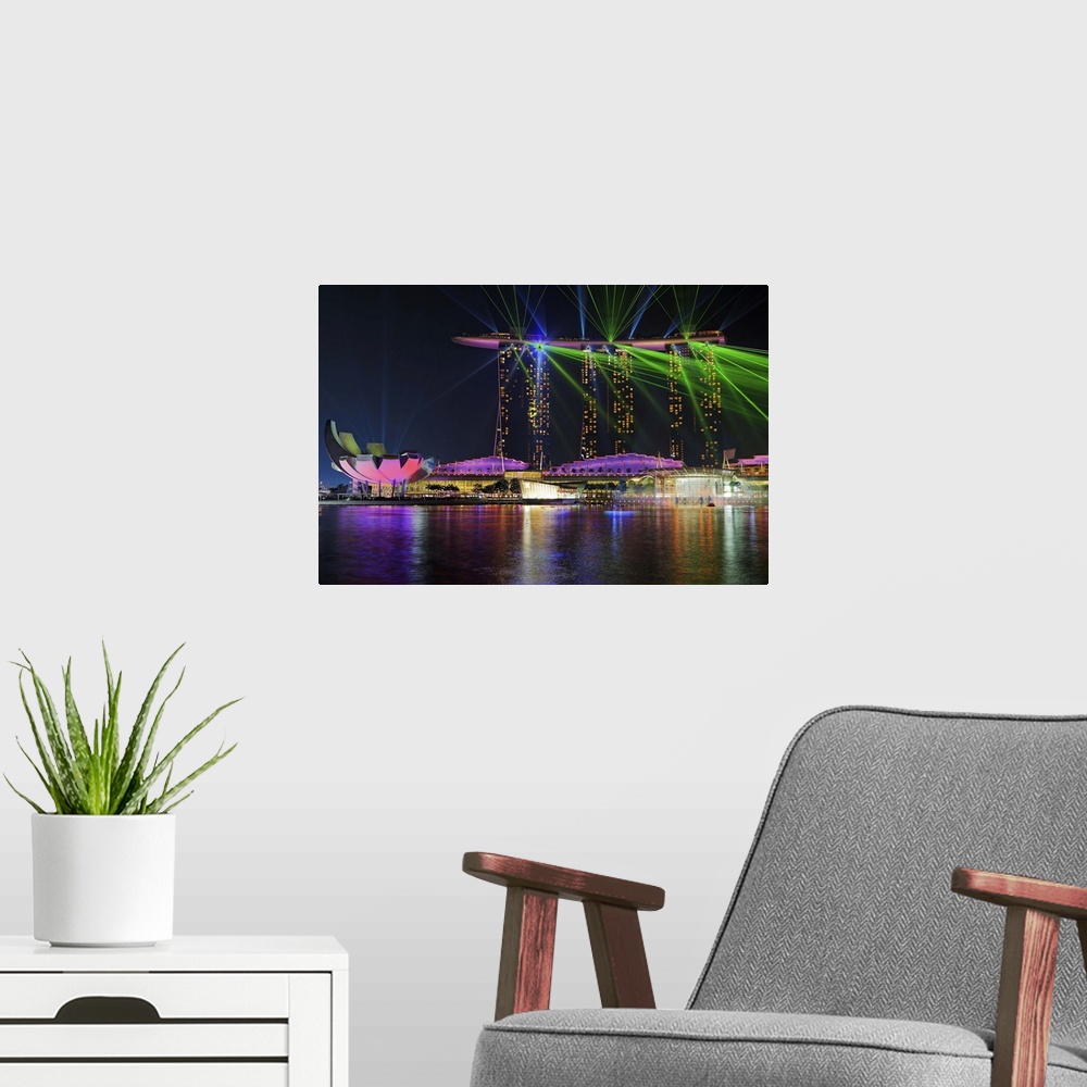 A modern room featuring The neon lights of the city enhance the vivid laser show on Marina Bay in Singapore.
