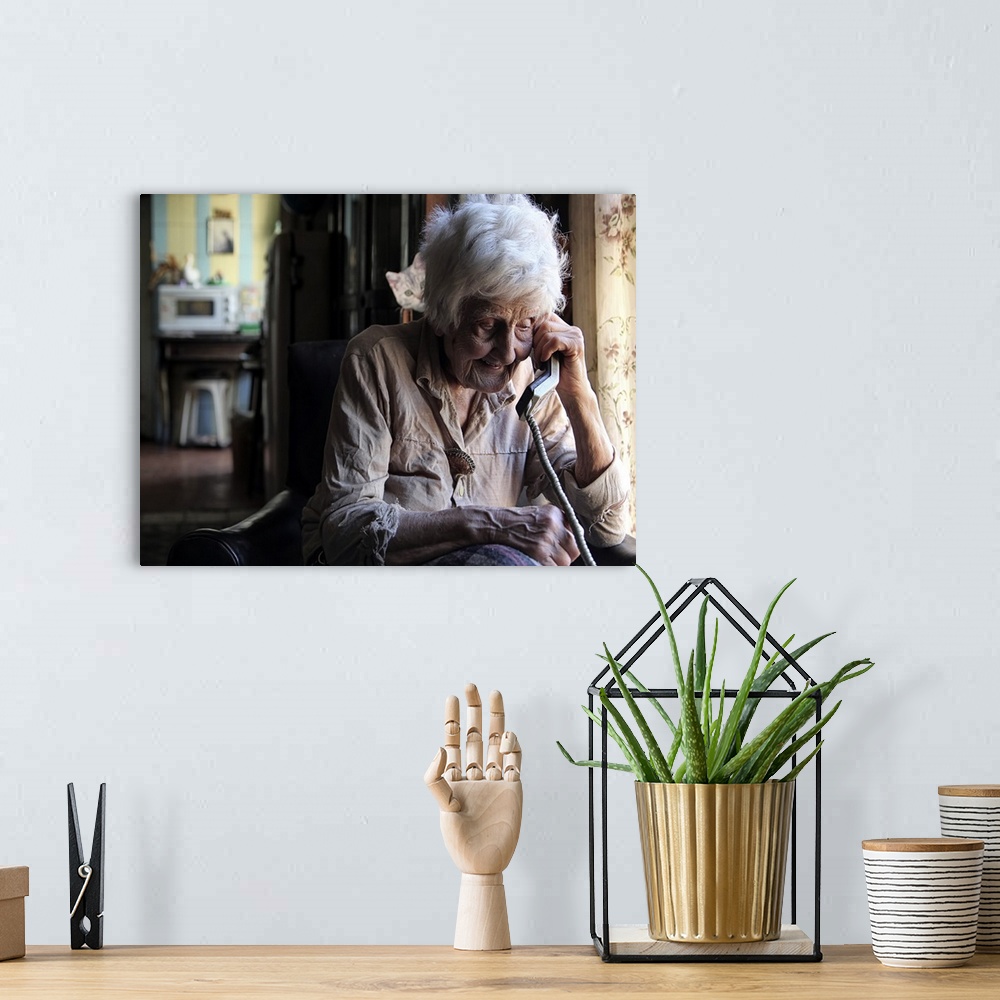 A bohemian room featuring Portrait of an elderly woman talking on a corded telephone.
