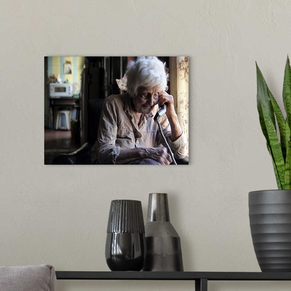 A modern room featuring Portrait of an elderly woman talking on a corded telephone.