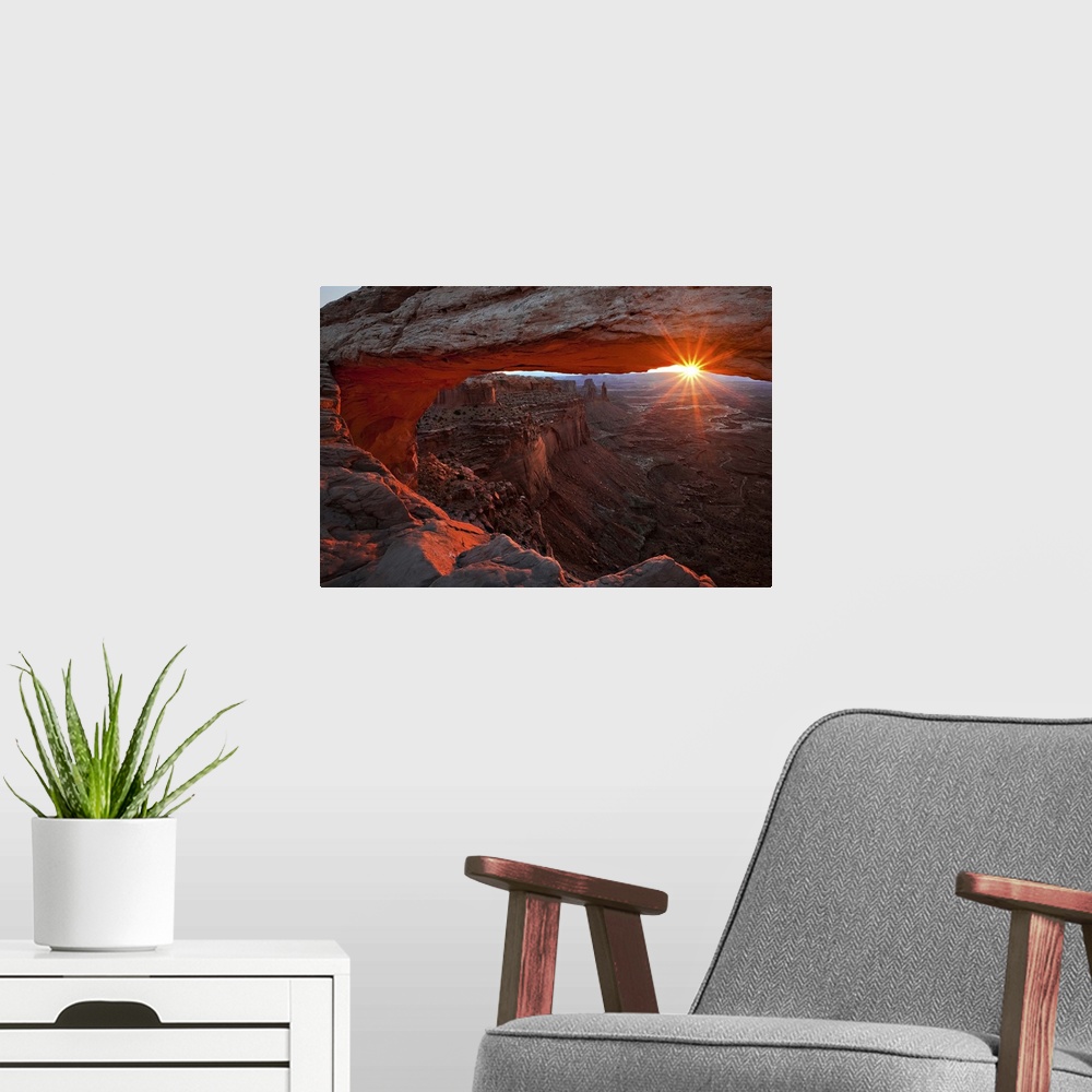 A modern room featuring The sun framed by a large natural arch and the horizon, Canyonlands National Park, Utah.