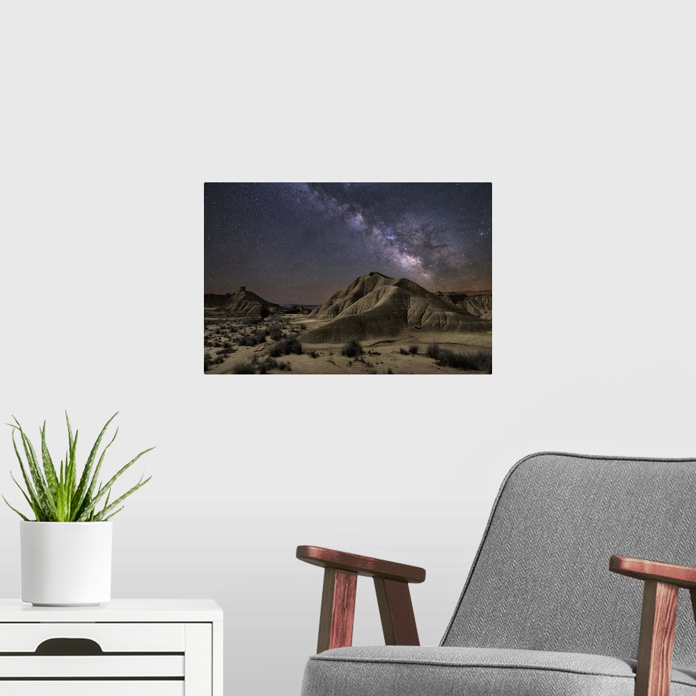 A modern room featuring The Milky Way galaxy illuminated over a rocky desert landscape.