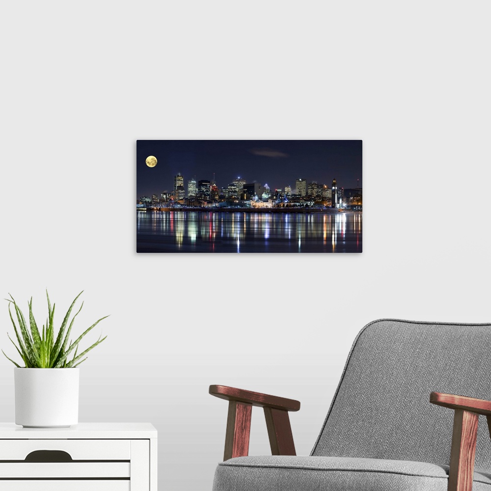 A modern room featuring Colorful city lights of the Montreal skyline reflected in the water at night.