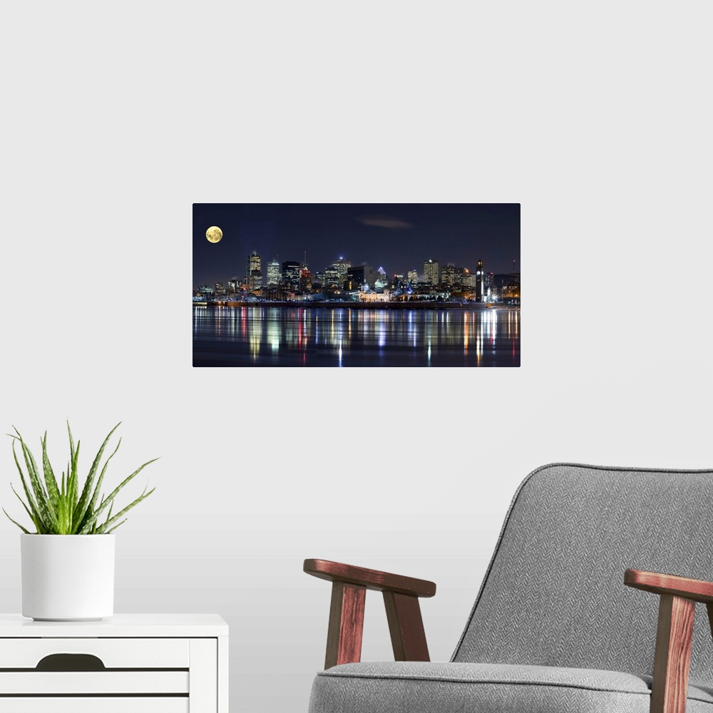 A modern room featuring Colorful city lights of the Montreal skyline reflected in the water at night.