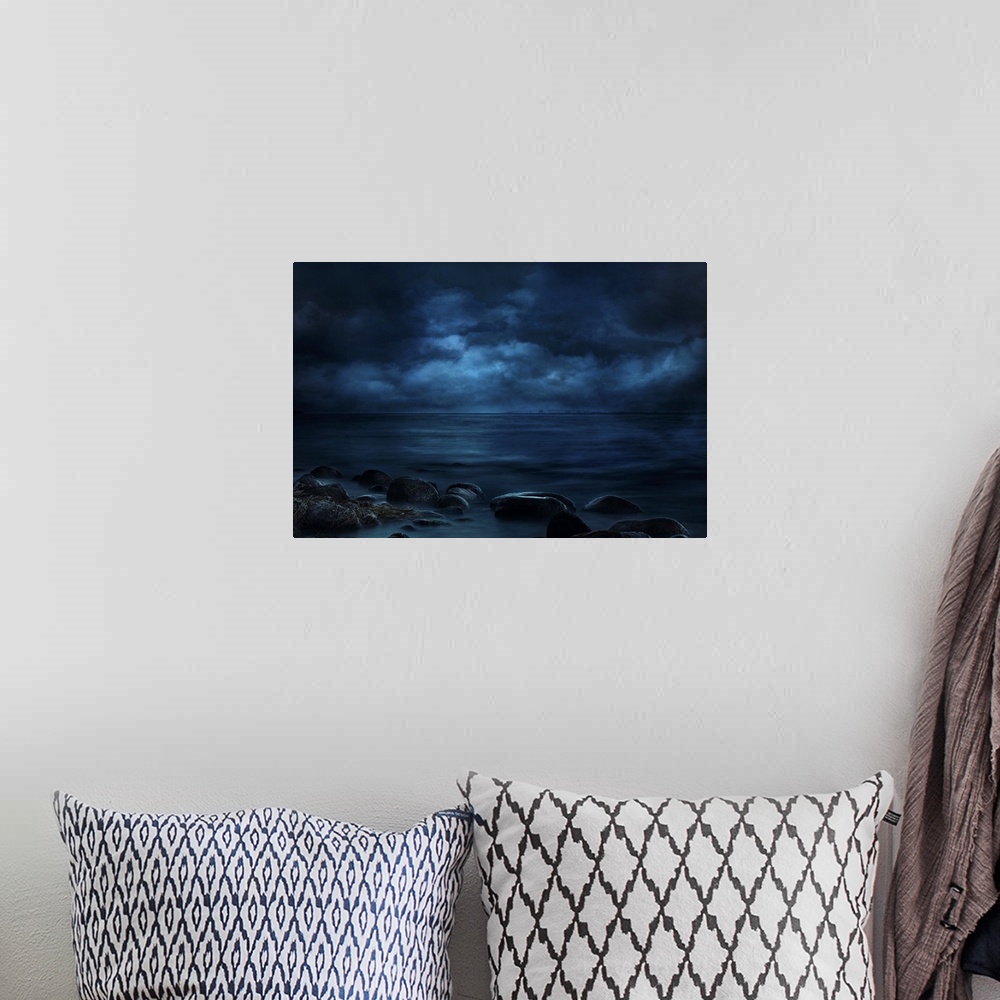 A bohemian room featuring Blue landscape photograph of a rocky seashore lit by moonlight with a bridge in the far distance.