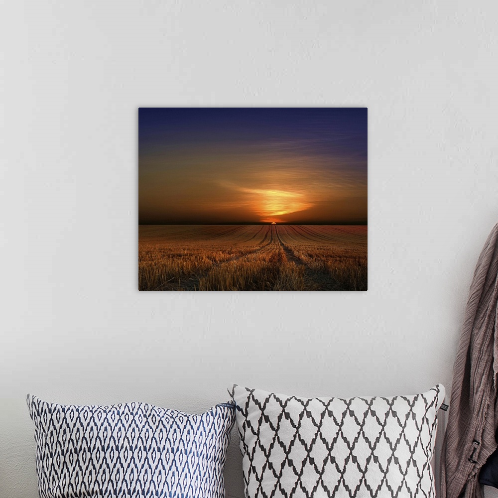 A bohemian room featuring The rising sun casts a bright glow on the clouds over a wheat field.