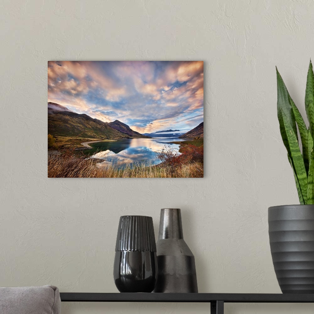 A modern room featuring Dramatic clouds hang over a mountain lake scene.