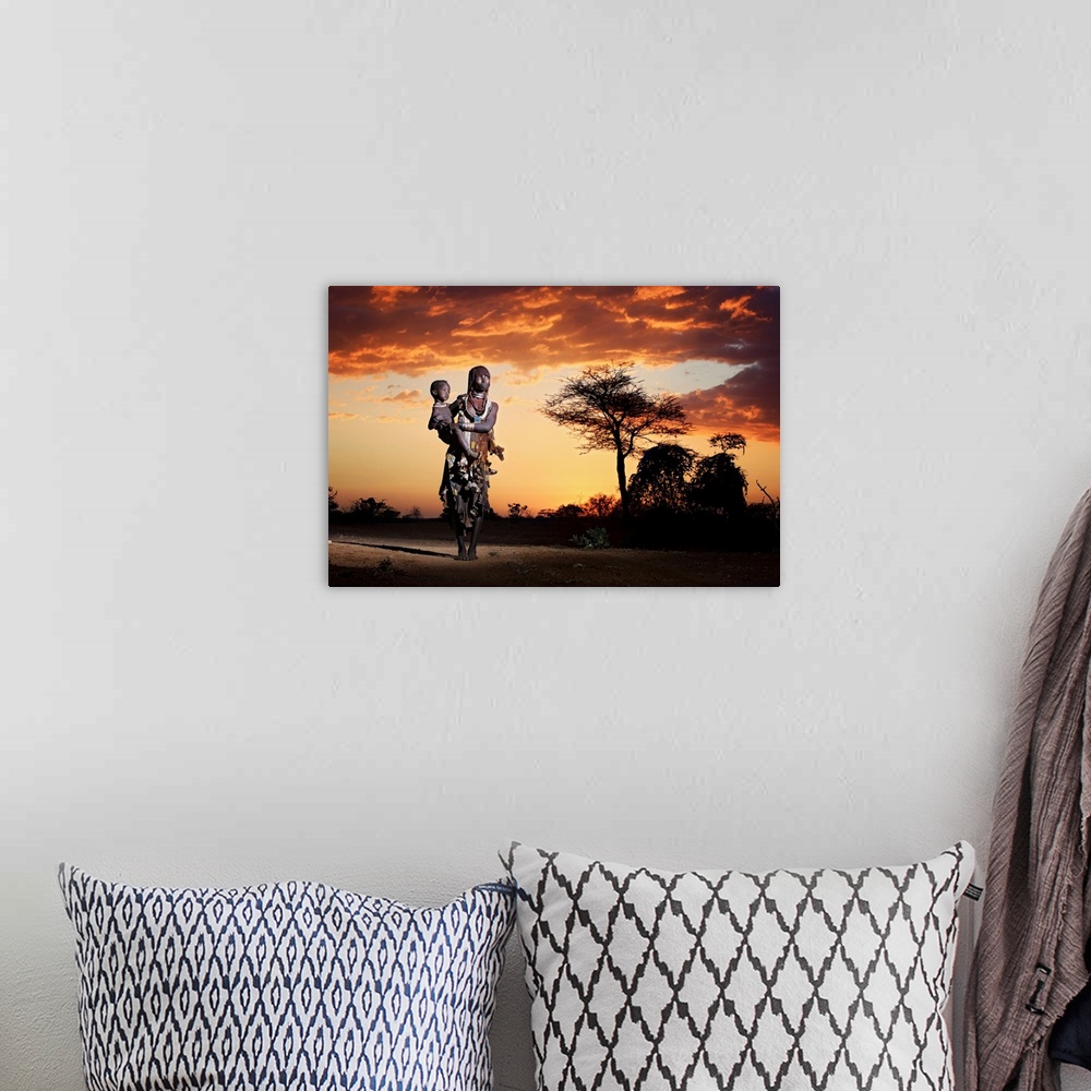 A bohemian room featuring A portrait of a tribes-woman holding her child underneath a sunset sky.