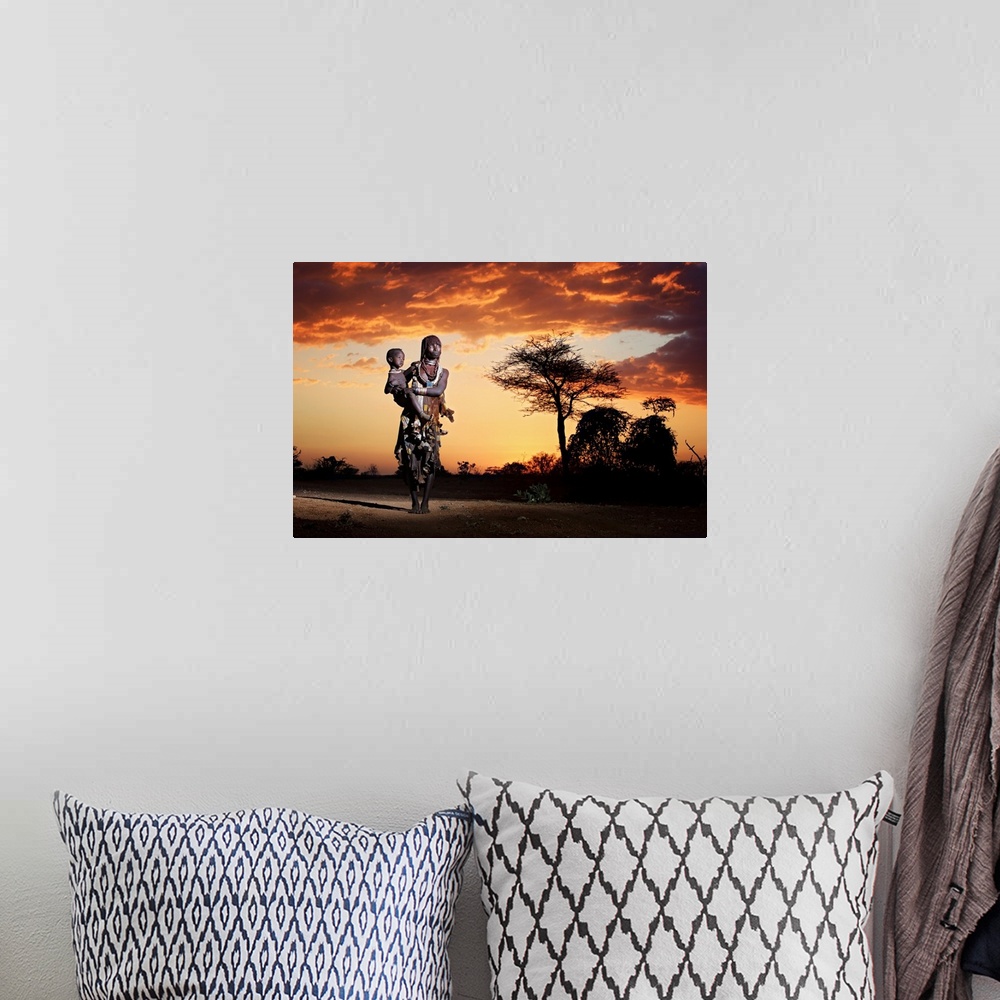 A bohemian room featuring A portrait of a tribes-woman holding her child underneath a sunset sky.