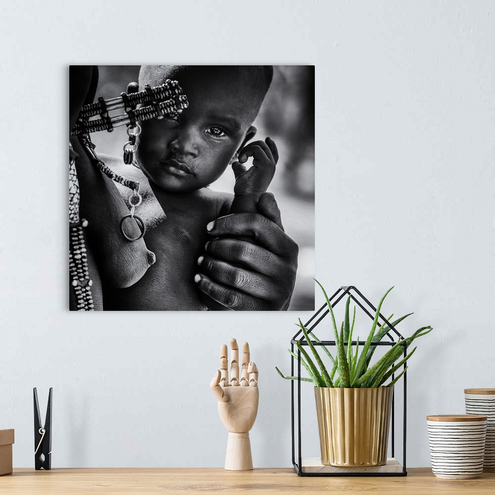 A bohemian room featuring A young Himba child stays close to their mother, Namibia.