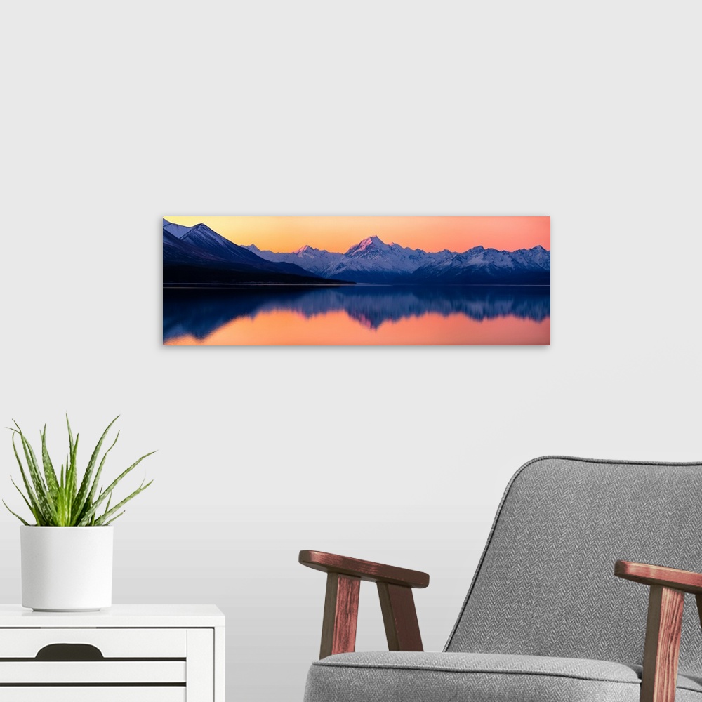 A modern room featuring Mount Cook at sunset reflecting in a lake below, New Zealand.