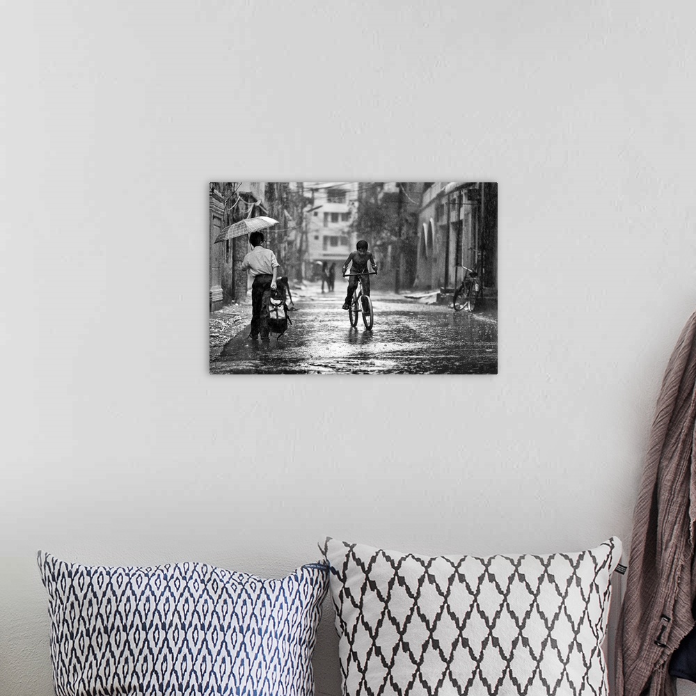 A bohemian room featuring A young boy riding his bike through the streets in the rain, Bangladesh.