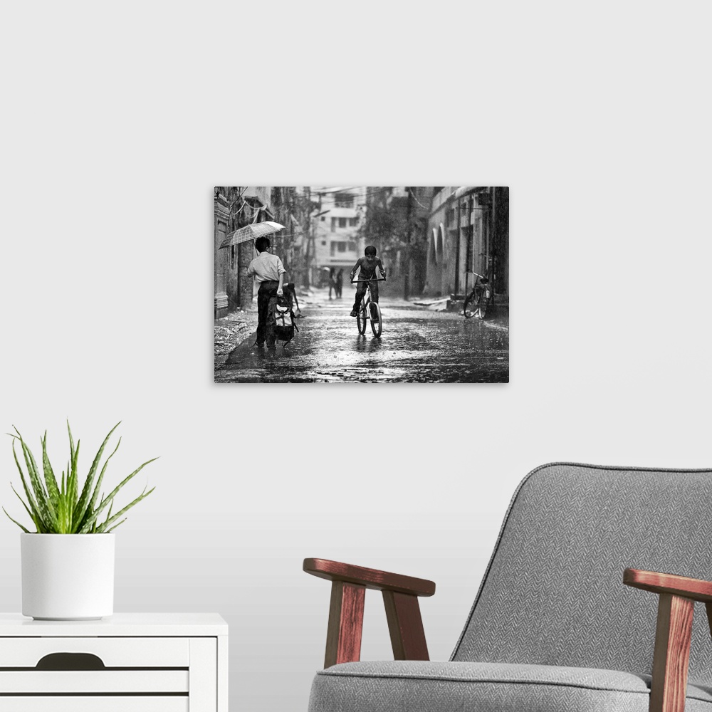 A modern room featuring A young boy riding his bike through the streets in the rain, Bangladesh.