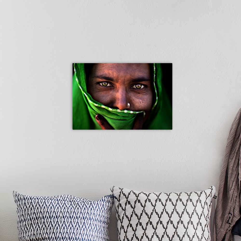 A bohemian room featuring A portrait of a woman with most of her face covered by a green wrap.