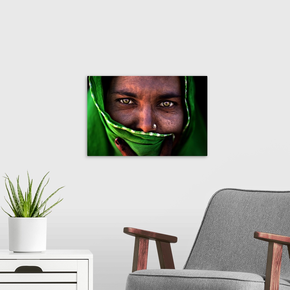 A modern room featuring A portrait of a woman with most of her face covered by a green wrap.