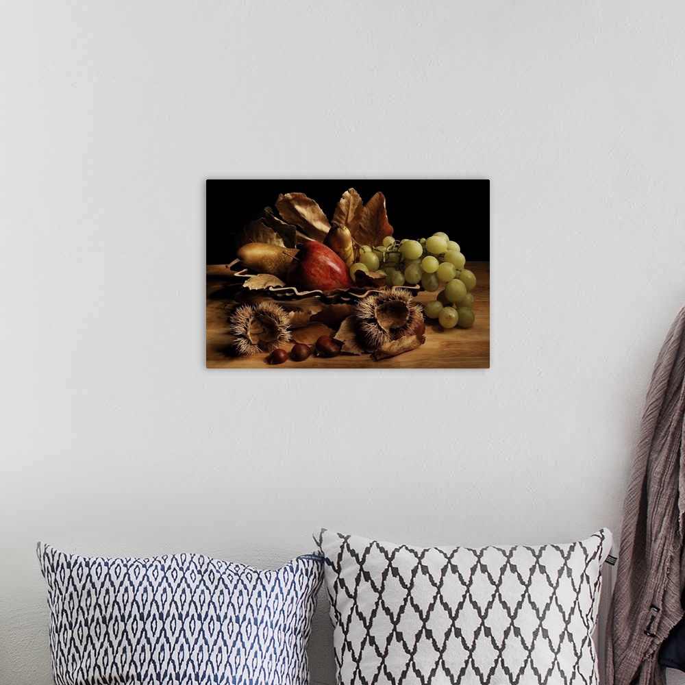A bohemian room featuring Still life arrangement with green grapes, a red apple, pears, fallen leaves, and chestnuts with t...