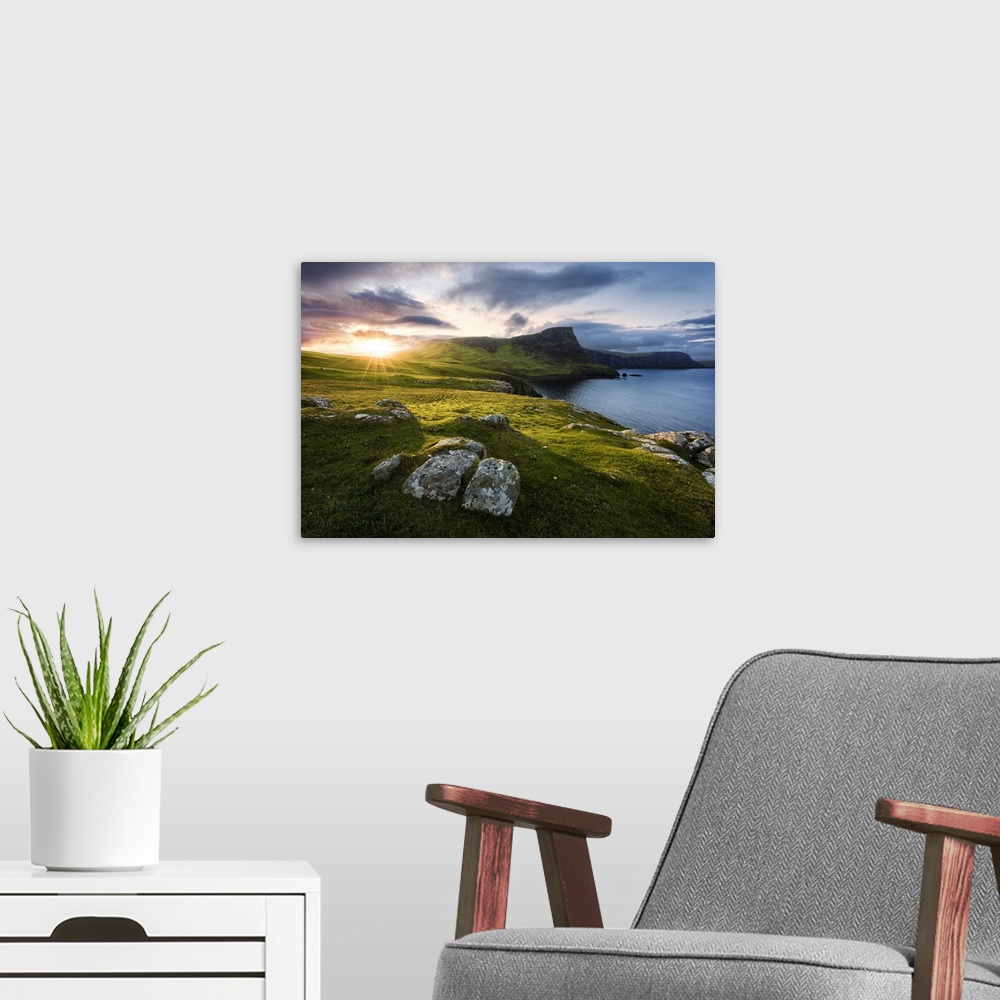 A modern room featuring A fine art photograph of a remote coastline in Scotland with the sun setting over the hills