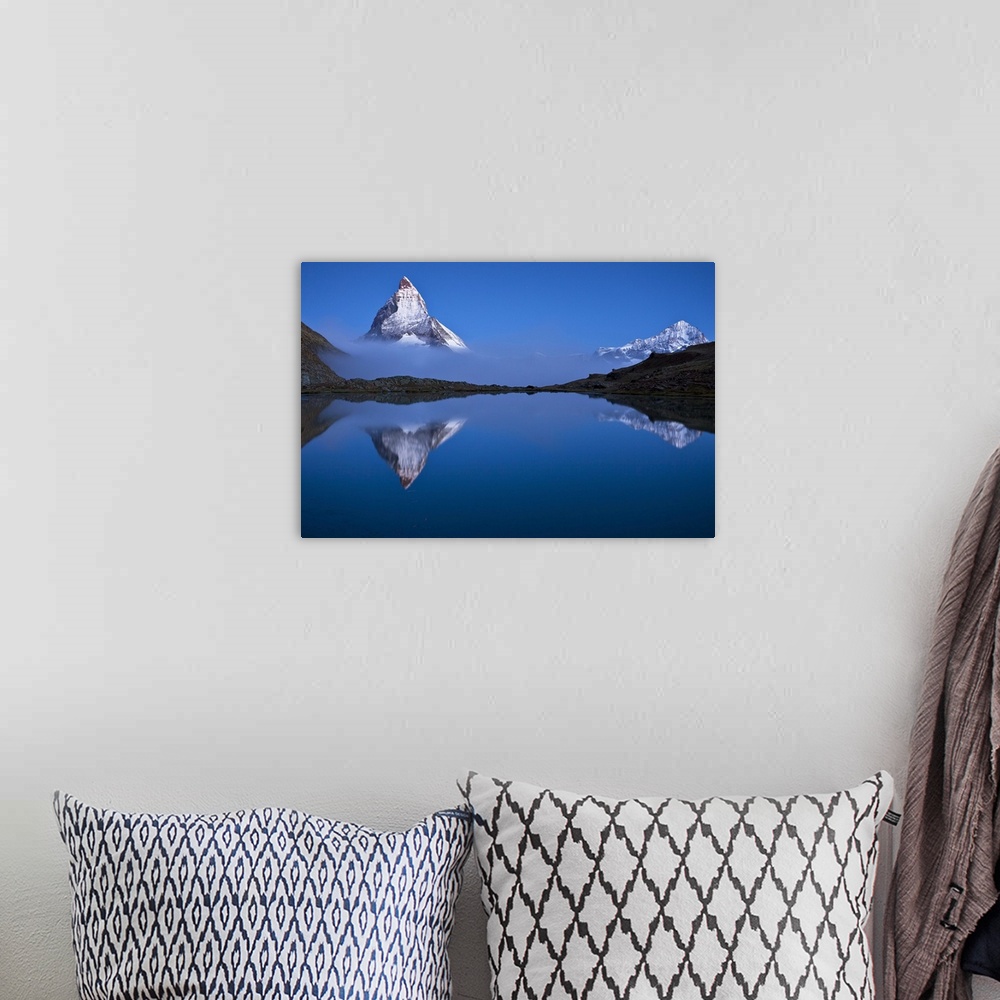 A bohemian room featuring A photograph of the Swiss Alps with the base of the Matterhorn covered in fog.