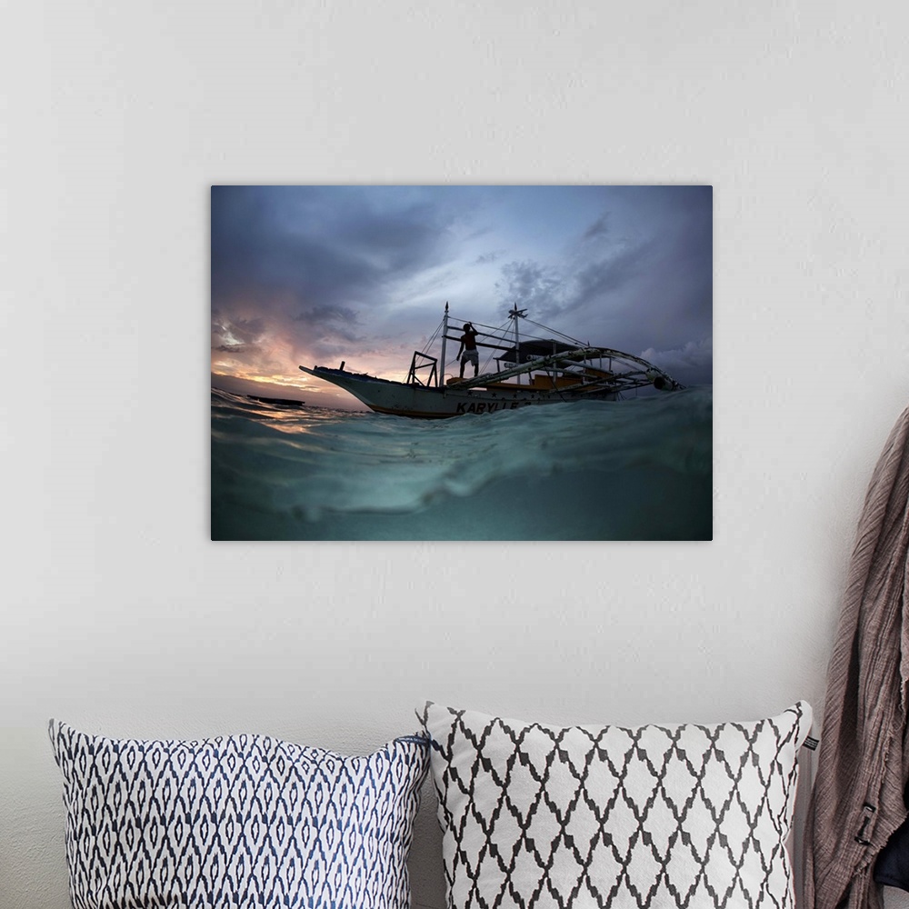 A bohemian room featuring View from the surface of the water of a figure on a boat at sunset, Philippines.