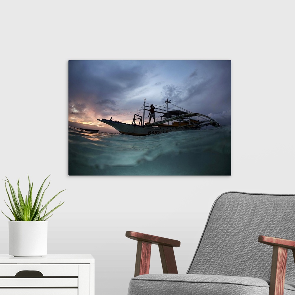 A modern room featuring View from the surface of the water of a figure on a boat at sunset, Philippines.