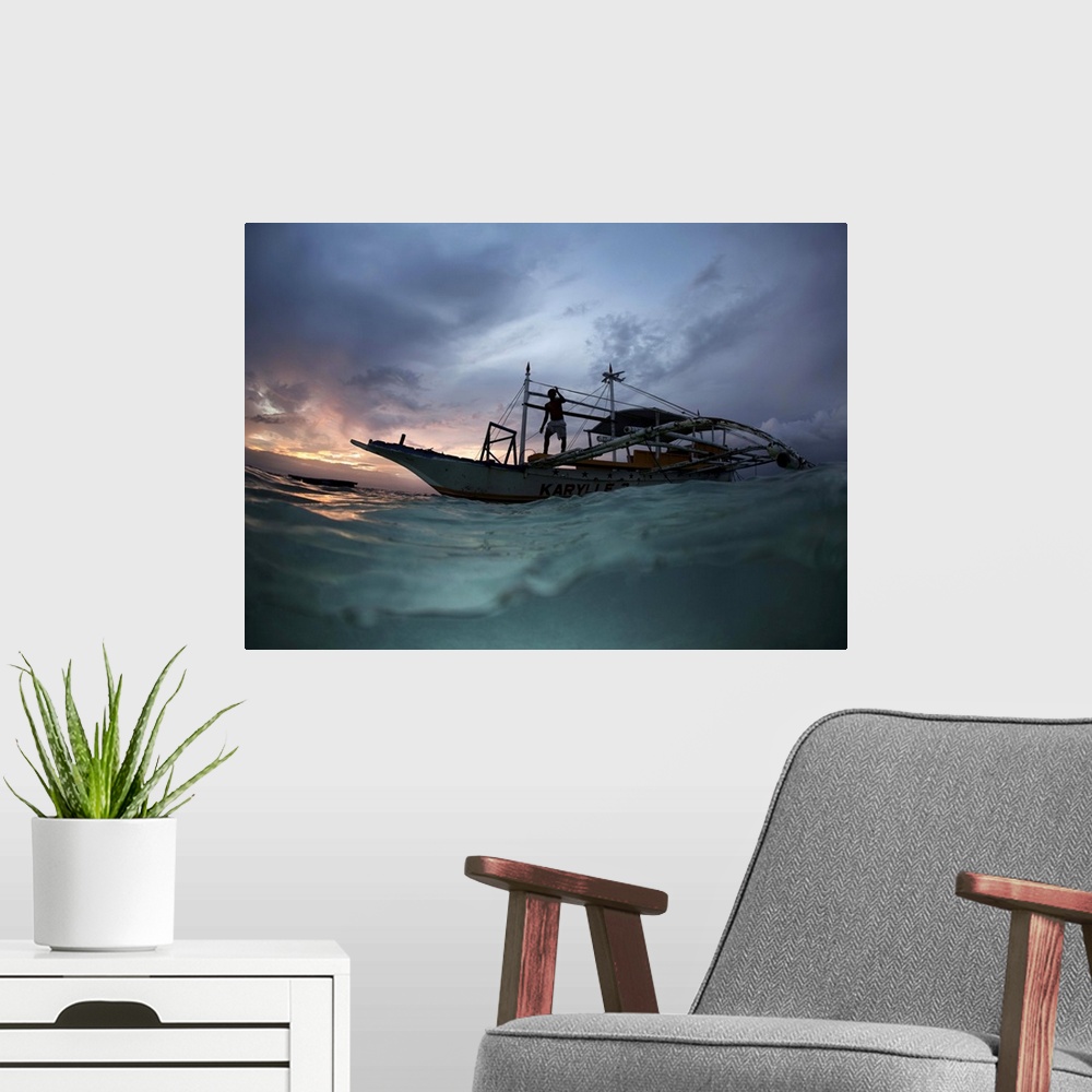 A modern room featuring View from the surface of the water of a figure on a boat at sunset, Philippines.