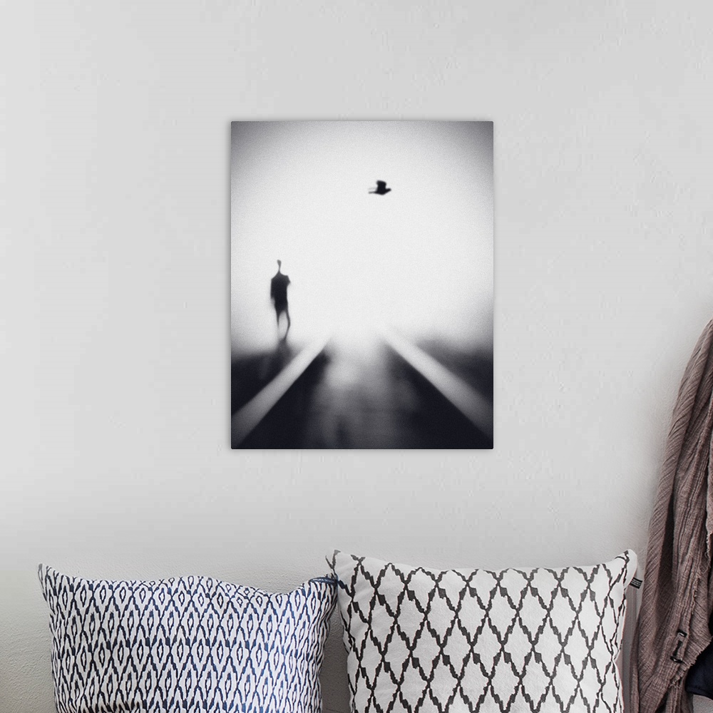 A bohemian room featuring Soft focus image of a man walking near rails with a bird overhead.