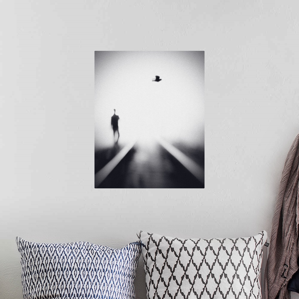 A bohemian room featuring Soft focus image of a man walking near rails with a bird overhead.