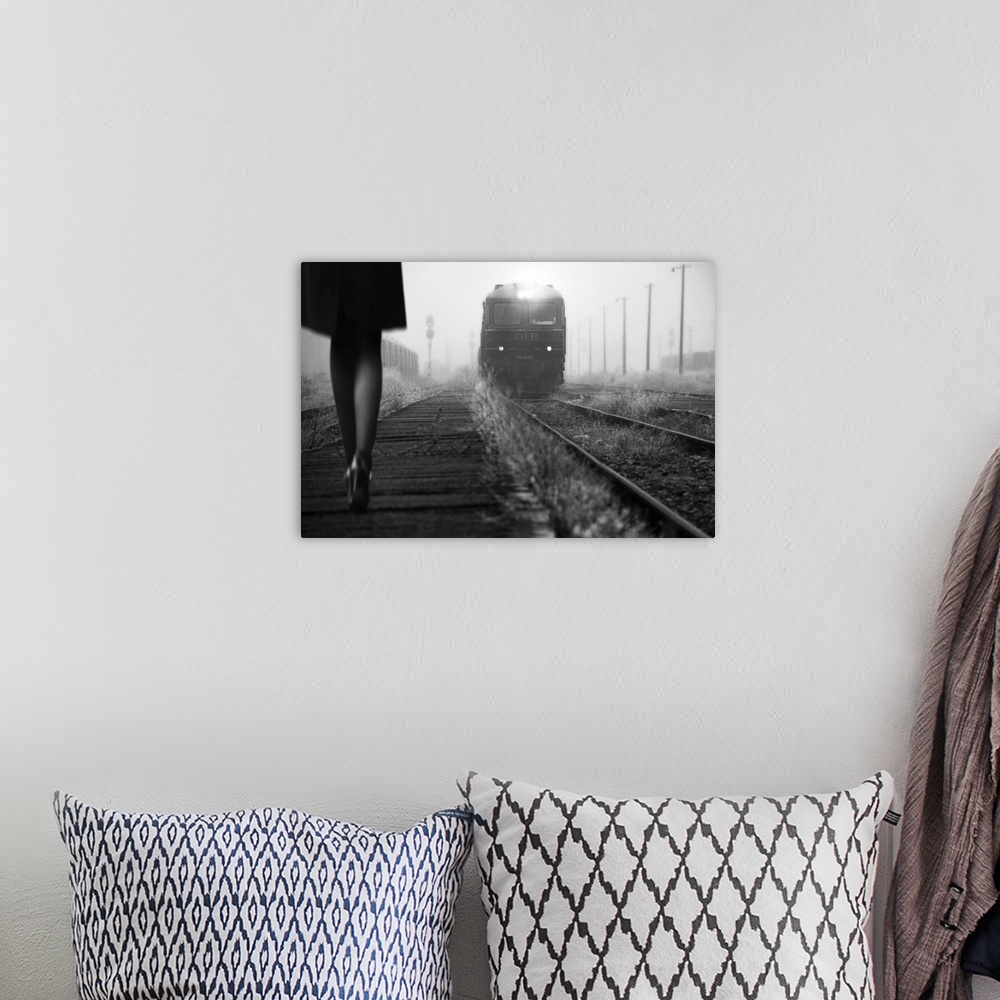 A bohemian room featuring Black and white image of a woman in heels talking along a path by railroad tracks with an approac...