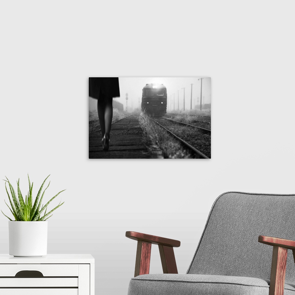 A modern room featuring Black and white image of a woman in heels talking along a path by railroad tracks with an approac...