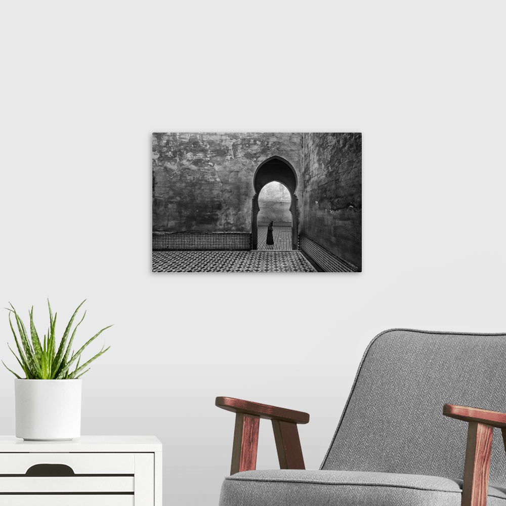 A modern room featuring A black and white photograph of a man passing by an archway.