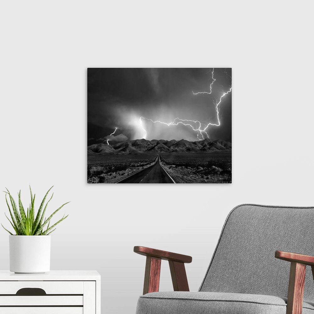 A modern room featuring A road leads to mountains in Nevada as lightning bolts shoot across the sky during  a thunderstorm.