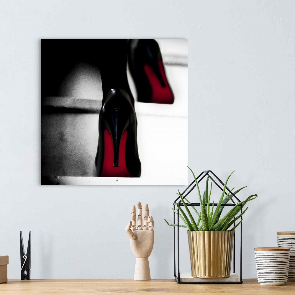 A bohemian room featuring Close up view of two black high heels with red soles walking up steps.