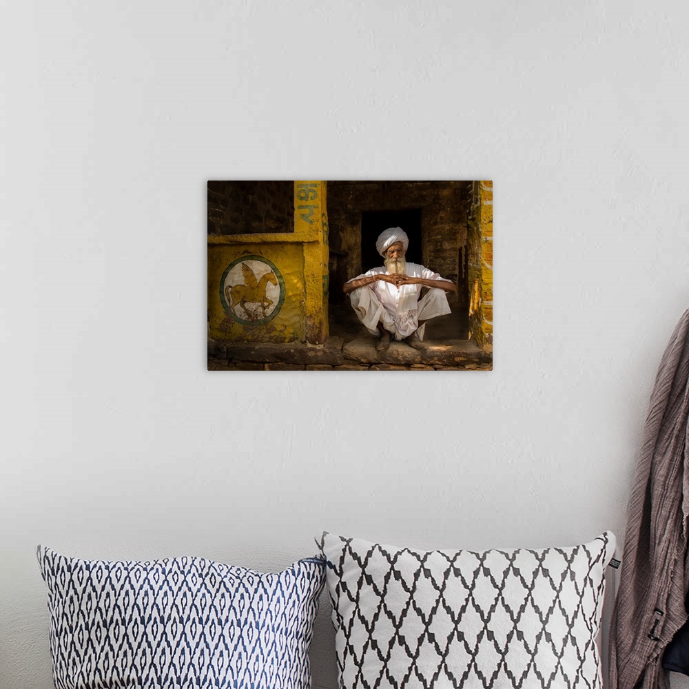A bohemian room featuring A portrait of a man sitting in a yellow doorway with a painting of a pegasus painted on the wall ...