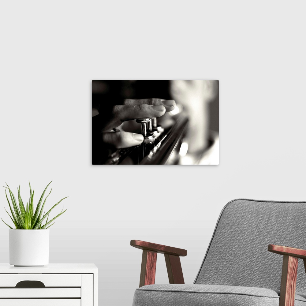 A modern room featuring Close up image of a person playing the trumpet, focusing on the fingers and buttons.