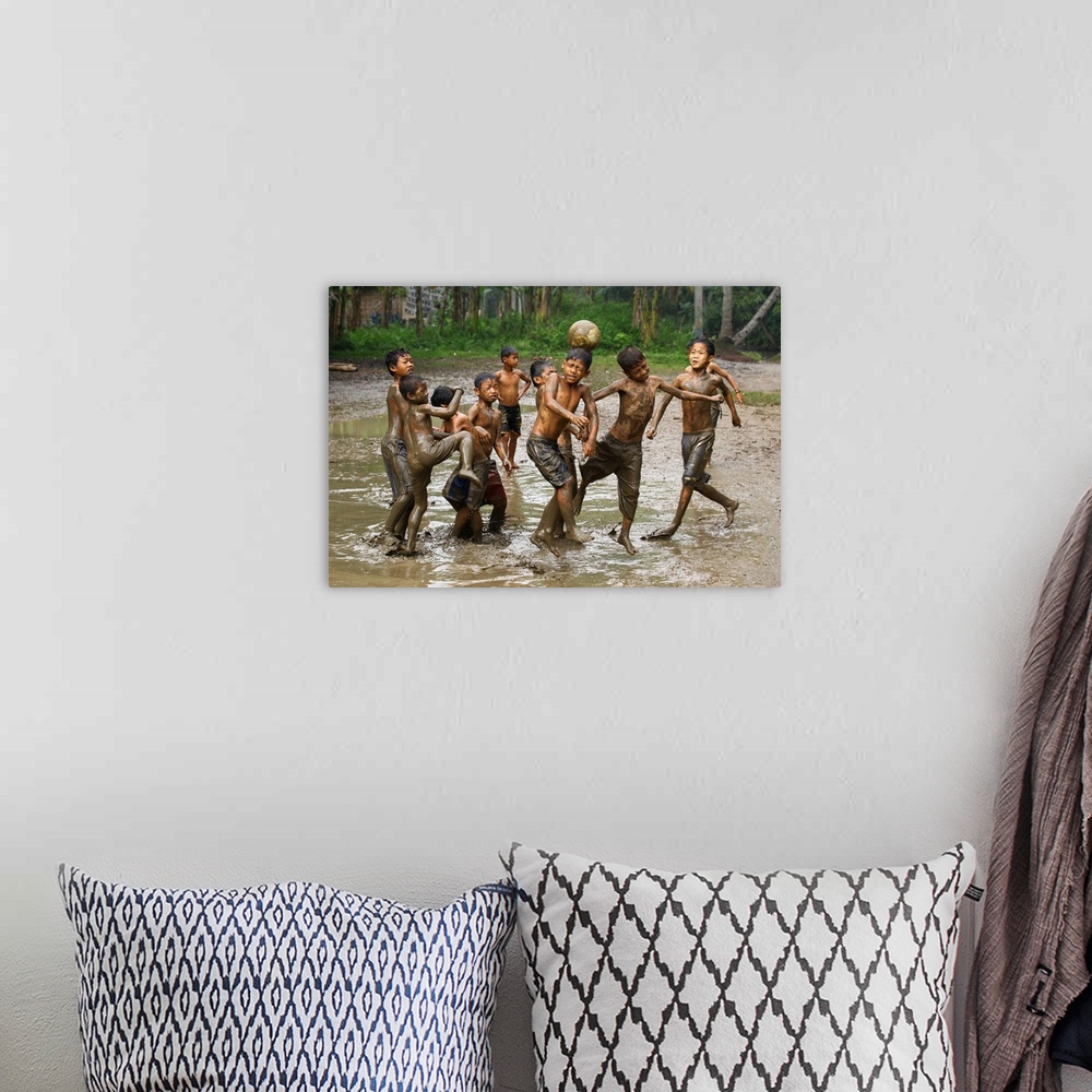 A bohemian room featuring A group of young boys playing soccer in muddy water.