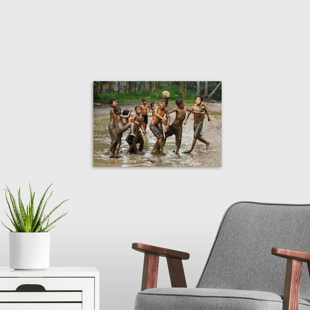 A modern room featuring A group of young boys playing soccer in muddy water.