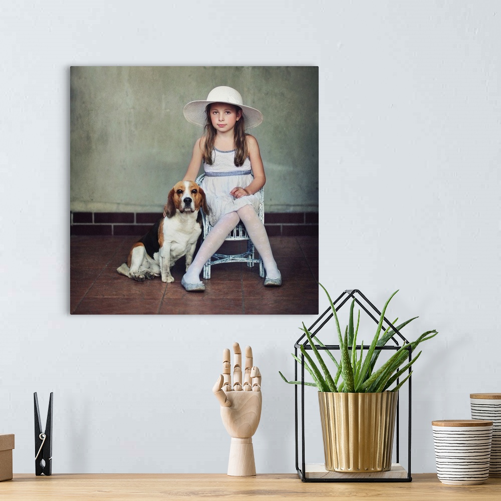 A bohemian room featuring A young girl in a dress and hat sitting on a chair with her pet beagle.