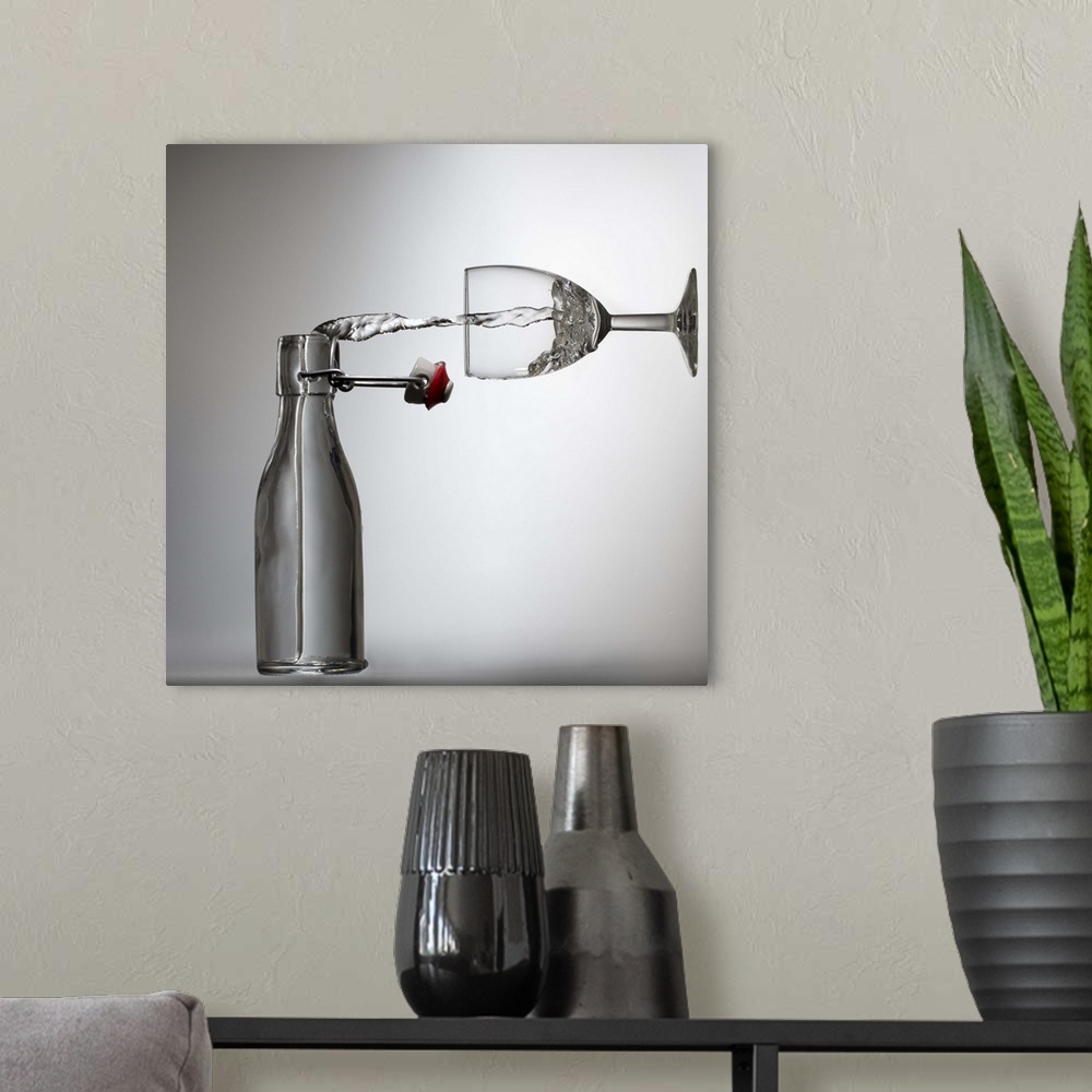 A modern room featuring Conceptual image of water being poured from a bottle into a glass, appearing sideways.