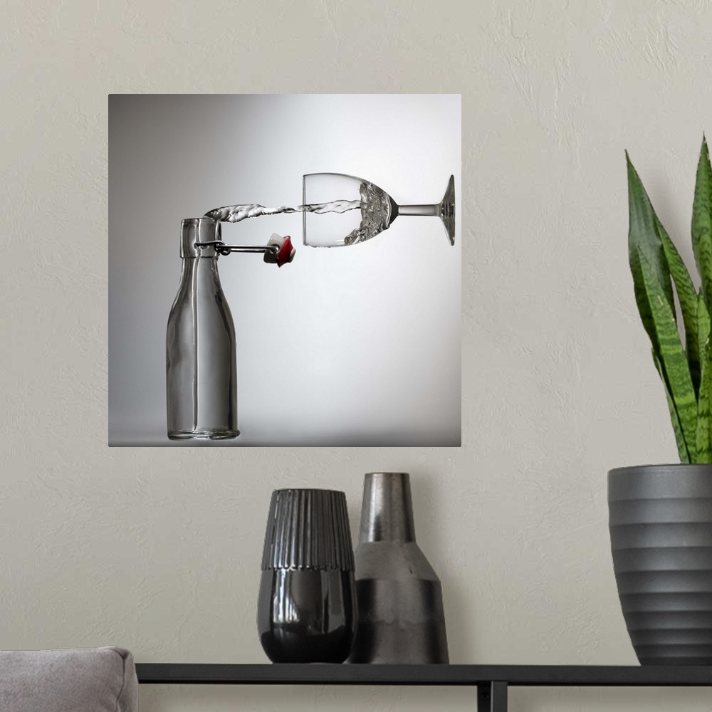A modern room featuring Conceptual image of water being poured from a bottle into a glass, appearing sideways.