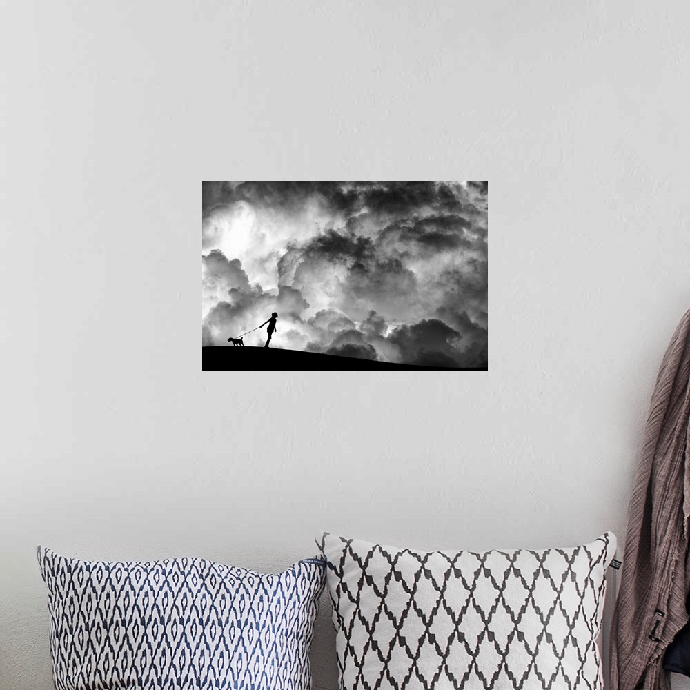 A bohemian room featuring A girl holding a dog on a leash in silhouette against a background of dramatic clouds.