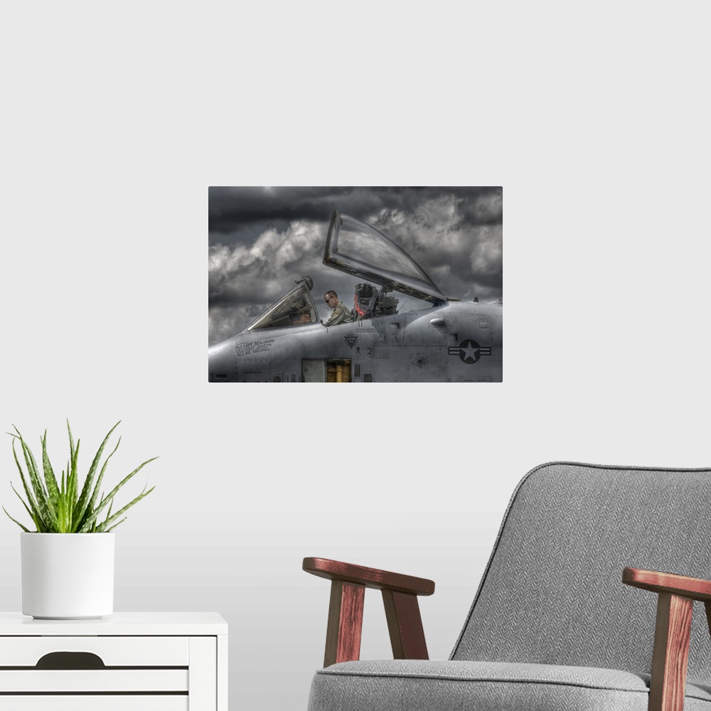 A modern room featuring A US Air Force pilot sitting in the cockpit of his plane with dark clouds overhead.