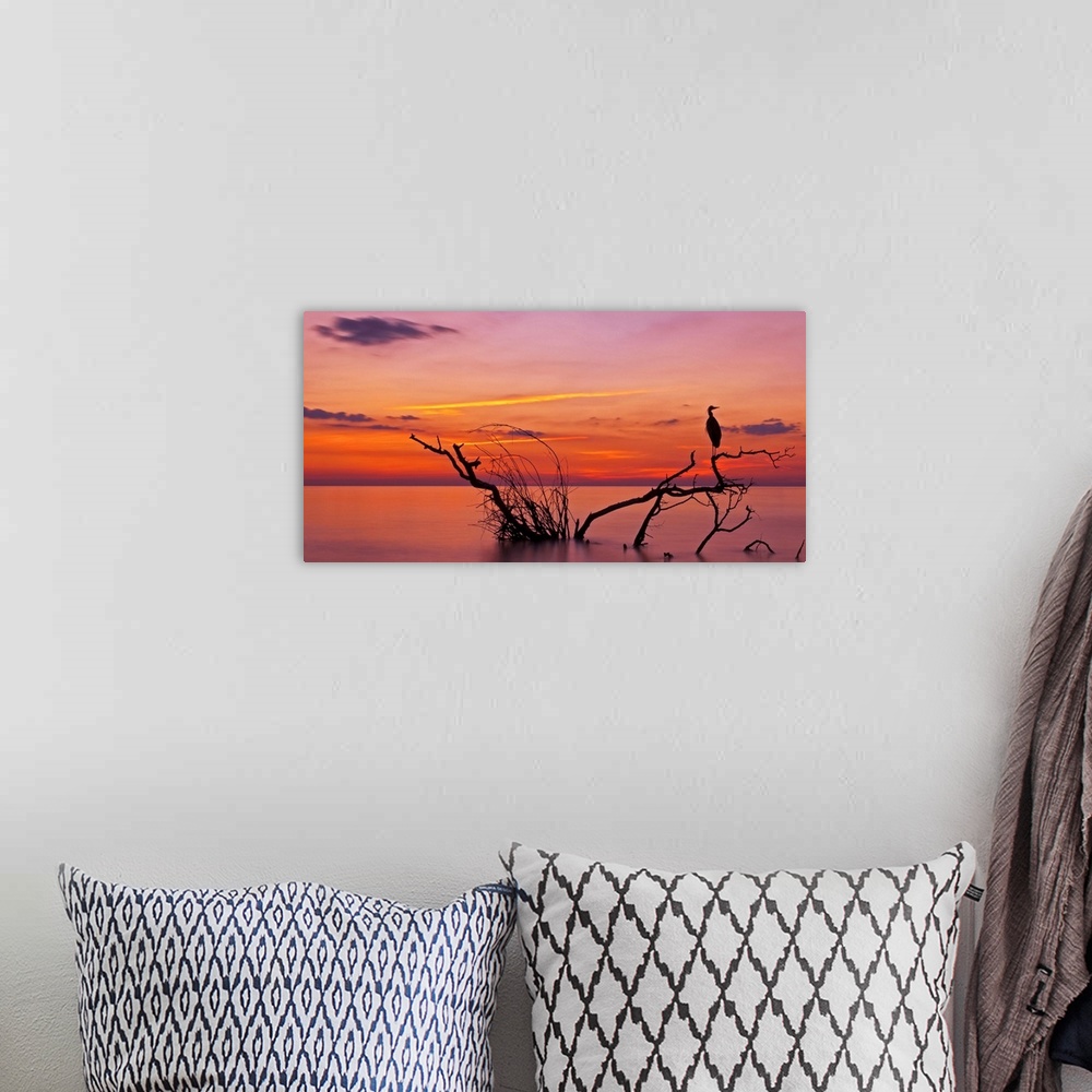 A bohemian room featuring Landscape photograph of a beautiful orange, red, yellow, purple and pink sunset over calm water.