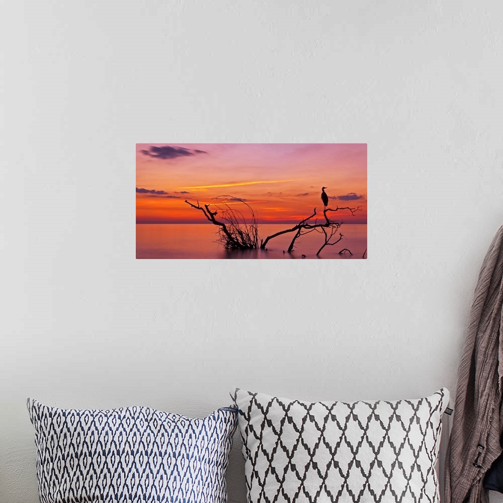 A bohemian room featuring Landscape photograph of a beautiful orange, red, yellow, purple and pink sunset over calm water.